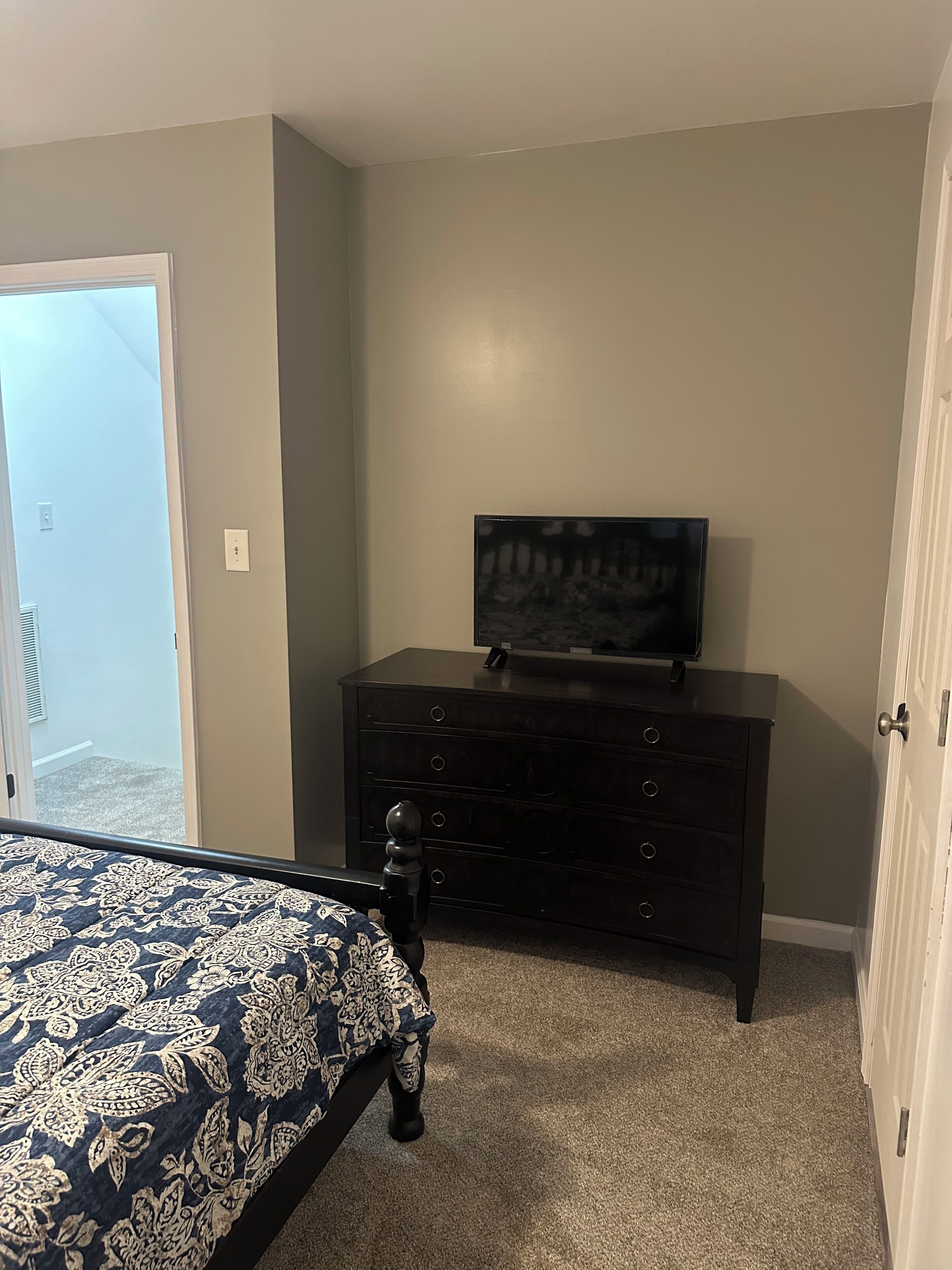 Un dormitorio con una cama, un aparador y un televisor sobre él.