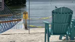 A view of a waterfront area with a chair and a sign indicating a no wake zone.