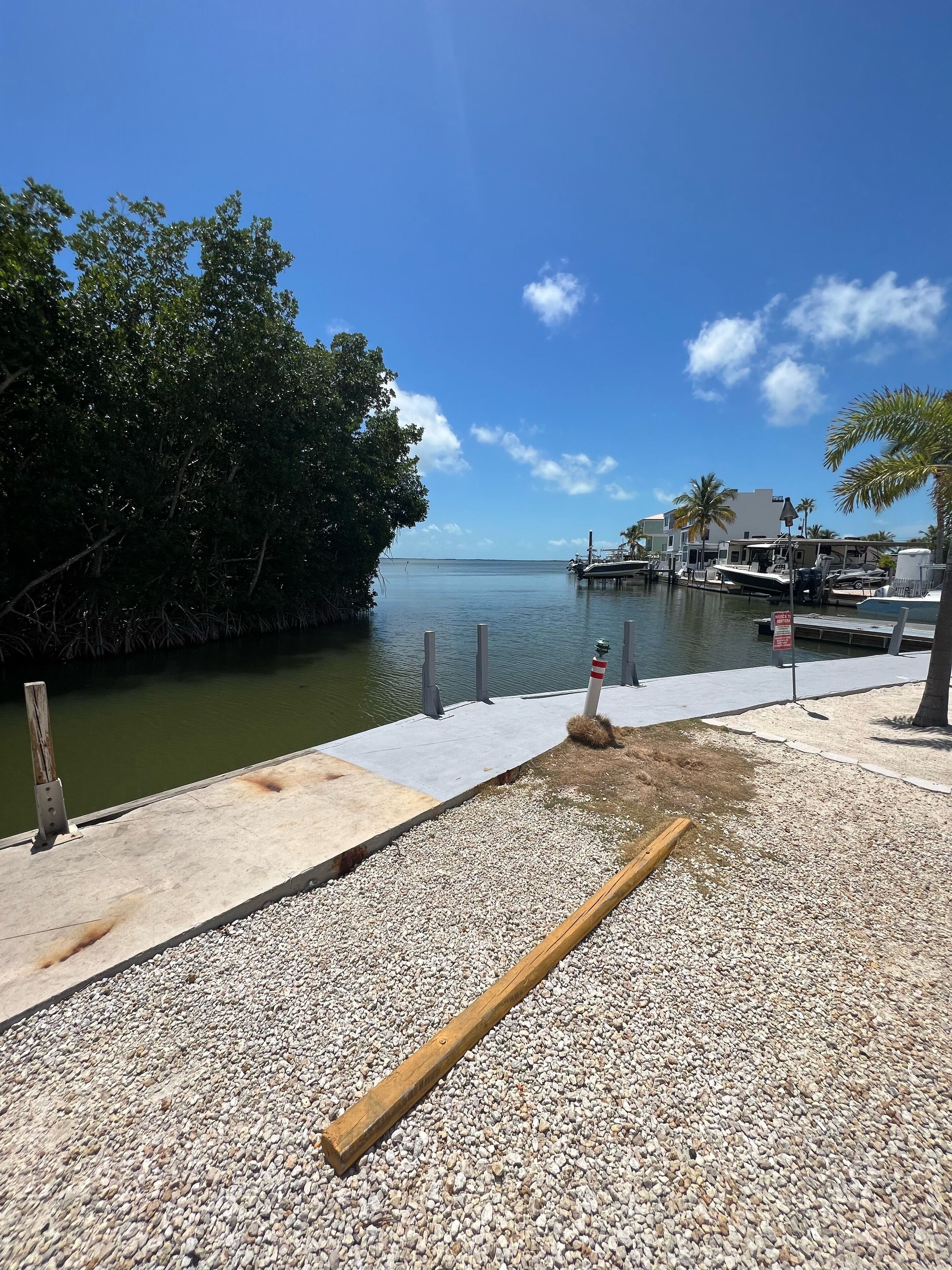 A waterfront dock with a boat, a wooden post, and a gravel path.