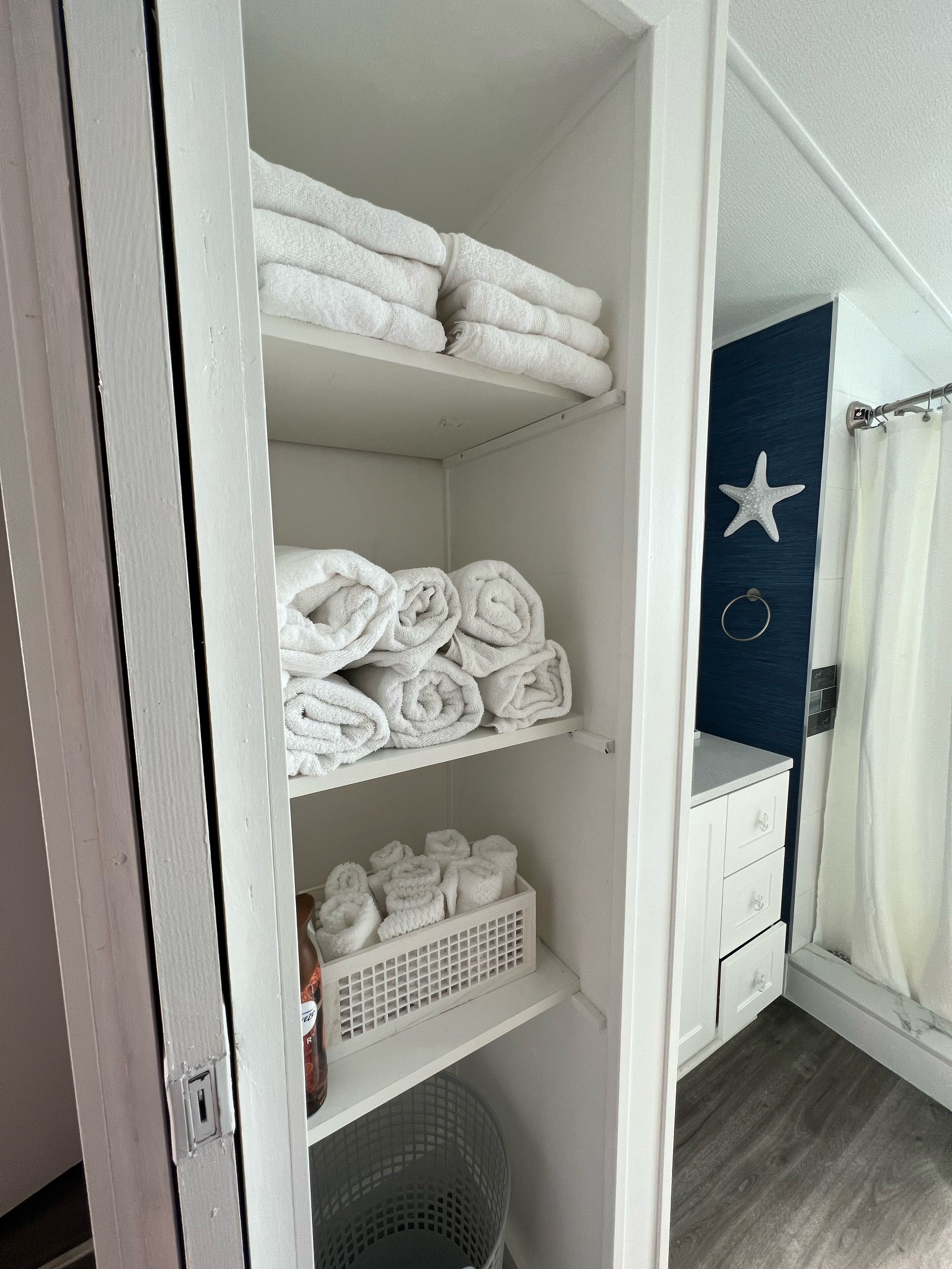 A neatly organized bathroom with a white vanity, a starfish decoration on the wall, and a shower curtain.