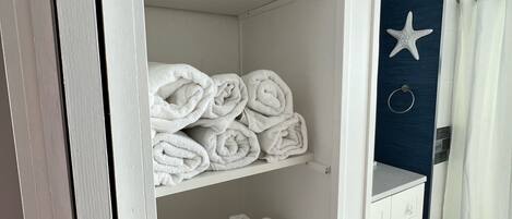 A neatly organized bathroom with a white vanity, a starfish decoration on the wall, and a shower curtain.