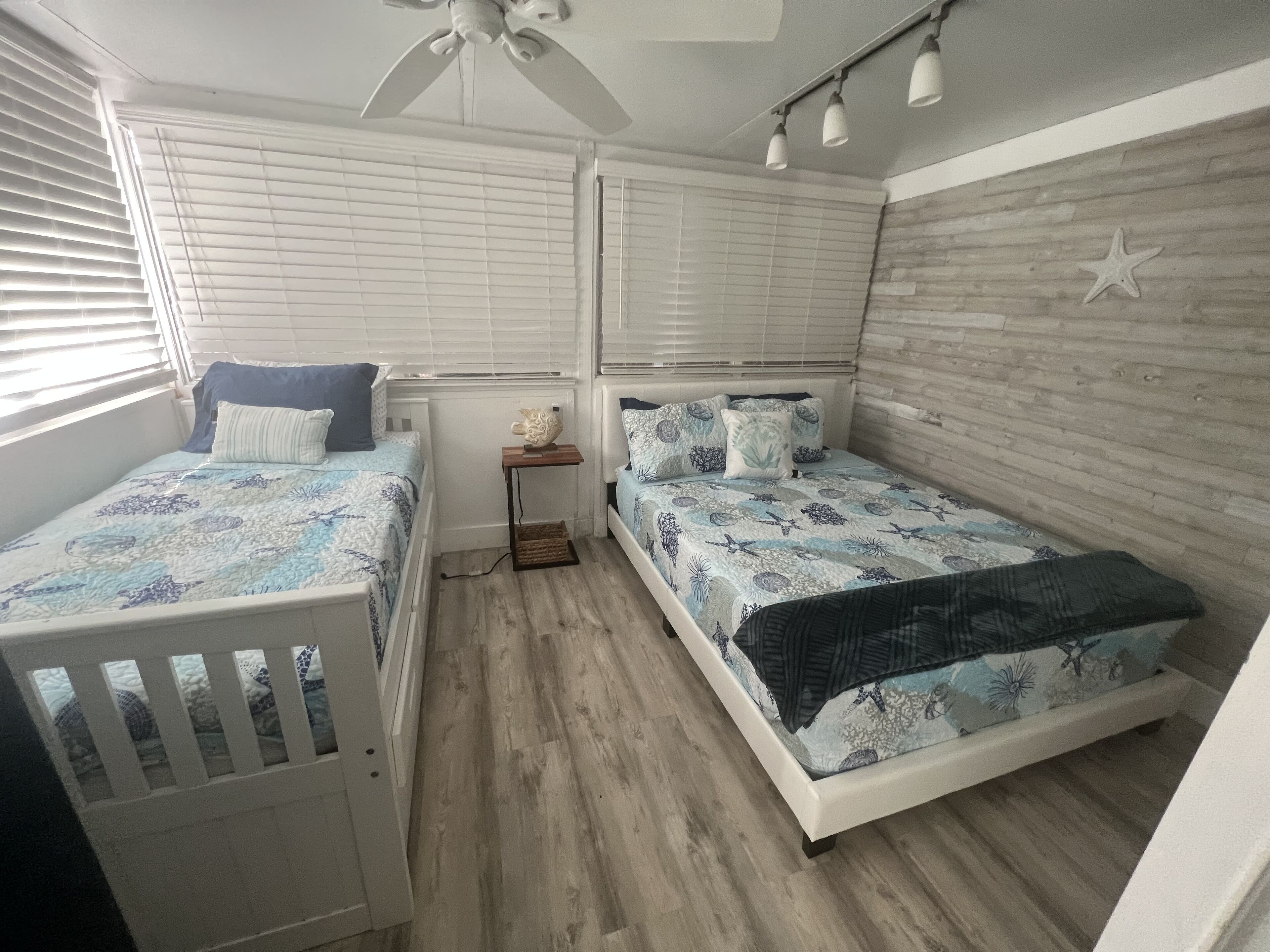 A bedroom with two beds, a ceiling fan, and a small table.