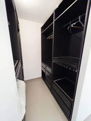 Ein begehbarer Kleiderschrank mit einer Spiegelklappe, einer Kleiderstange und einem eingebauten Regal.