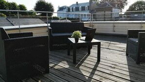 A rooftop deck with outdoor furniture, including a sofa and a table with a laptop and a plant. - Le Canyon Rouen Centre by MyFrenchPAT Votre Escapade Terrasse! Parking possible
 (Rouen)