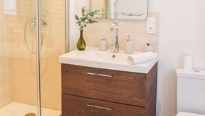 A bathroom with a glass shower enclosure, a wooden vanity with a mirror, and a toilet. - Le Canyon Rouen Centre by MyFrenchPAT Votre Escapade Terrasse! Parking possible
 (Rouen)