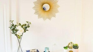 A white fireplace with a gold mirror above it, a vase with white flowers, and a small table with a candle and a book. - Le Canyon Rouen Centre by MyFrenchPAT Votre Escapade Terrasse! Parking possible
 (Rouen)