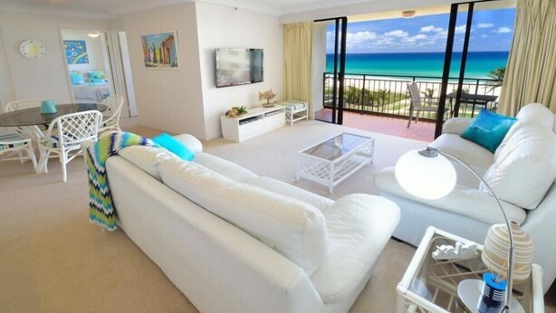 A modern hotel room with a large balcony, white furniture, and a view of the ocean. - Ocean View Waterfront Apartment Gold coast (gold coast)