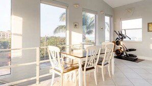Un comedor con una mesa y sillas, ventanas amplias con vistas y una bicicleta estática.