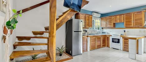 A modern kitchen with wooden cabinets, a stainless steel refrigerator, and a built-in stove.