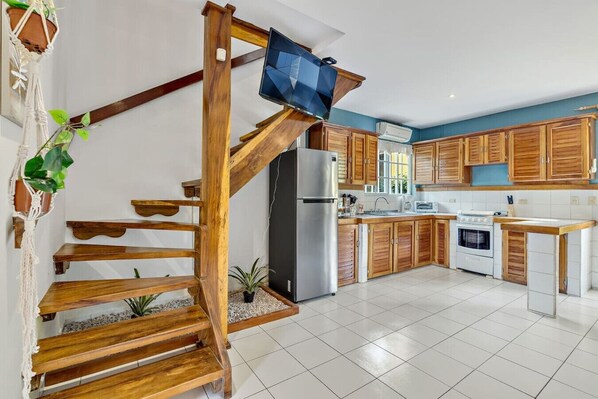 A modern kitchen with wooden cabinets, a stainless steel refrigerator, and a built-in stove.