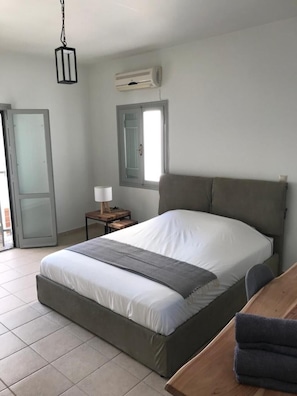 Ein Schlafzimmer mit Bett, Nachttisch, Lampe, Klimaanlage und Fenster.