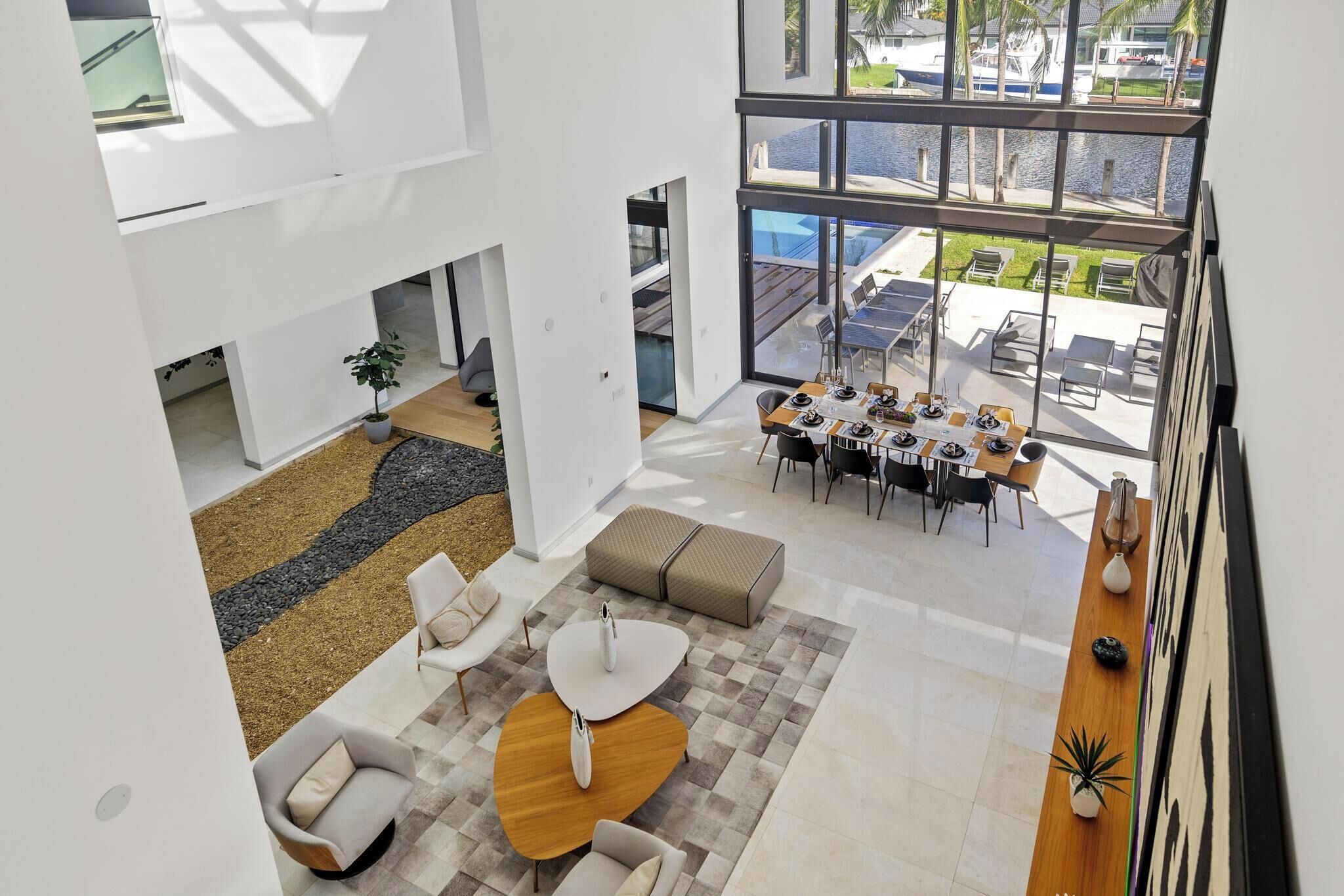 A spacious, modern interior with a dining area, seating, and a view of the outdoor pool.