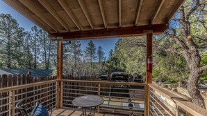 Un patio al aire libre con barandillas de madera, una parrilla y mobiliario.