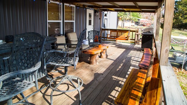 Un patio couvert, aménagé avec du mobilier d’extérieur, notamment des chaises et des tables, et doté d’un barbecue.