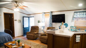 Un espace de vie compact comprenant une kitchenette, un coin repas et une chambre.
