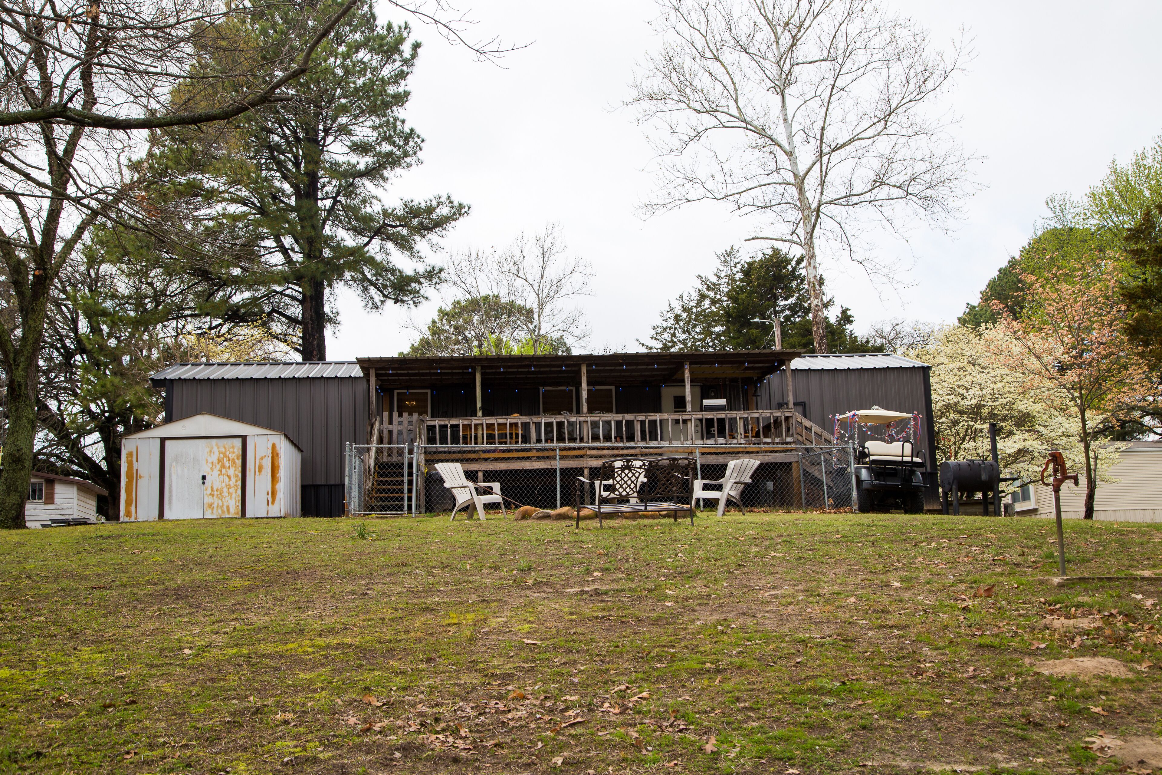 A rustic outdoor area with a wooden deck, a covered seating area, and a small shed.