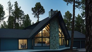 Una casa moderna con chimenea de piedra, ventanas amplias y un patio.