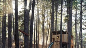 Una casita de juegos de madera con un tobogán en un bosque.