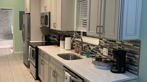 A modern kitchen with stainless steel appliances, a large island with a sink, and a tiled backsplash.
