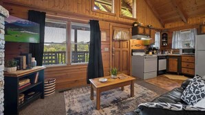 A cozy cabin with a wooden interior, a dining area, and a kitchen. - Location! Cute Studio Log Cabin,Fireplace, Hot Tub (Pigeon Forge)