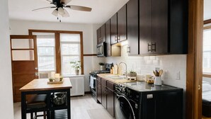 Una cocina compacta con zona de comedor, ventilador de techo y vistas por una ventana.