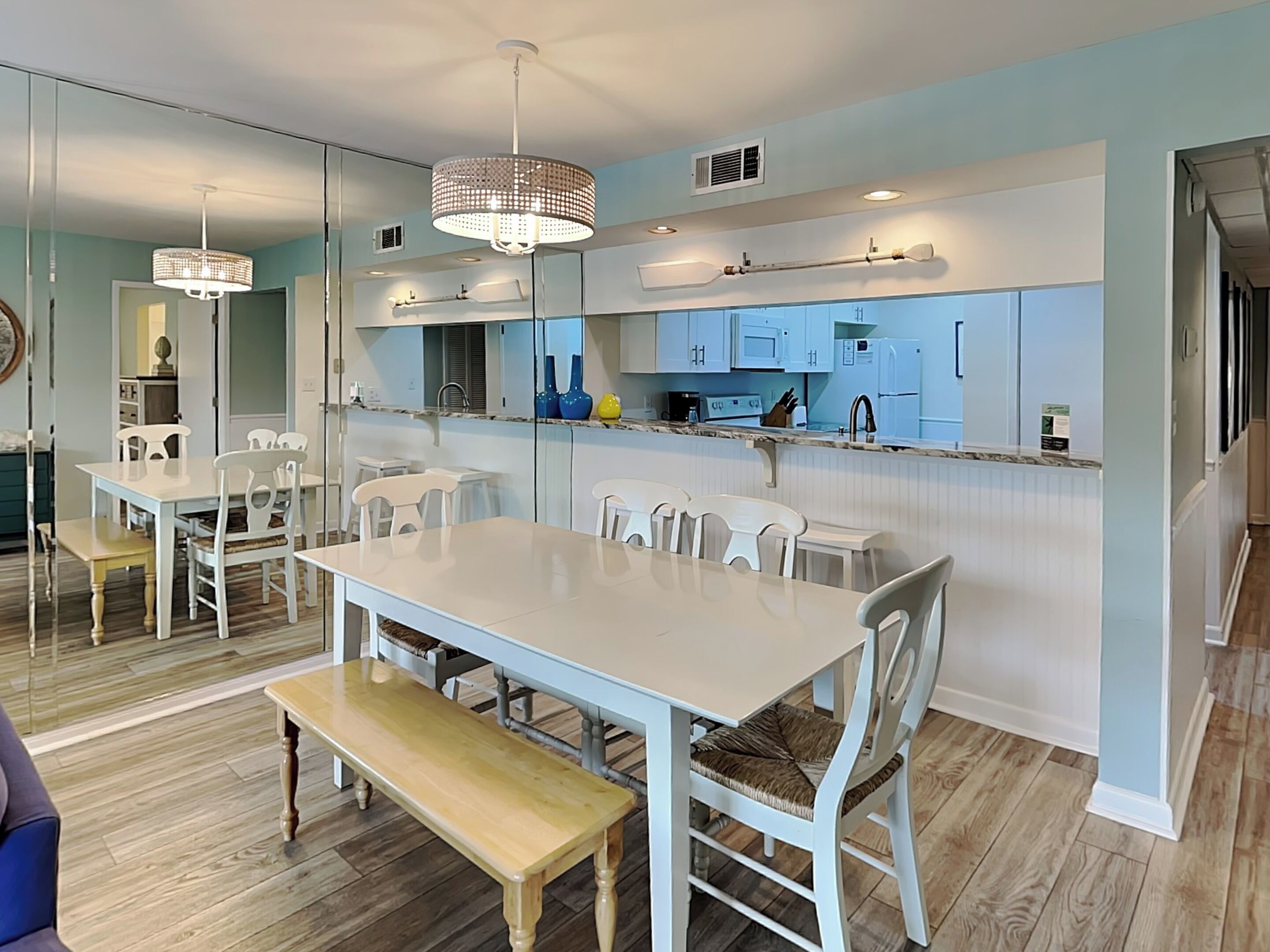 A modern kitchen with white cabinetry, a central island, and pendant lighting.