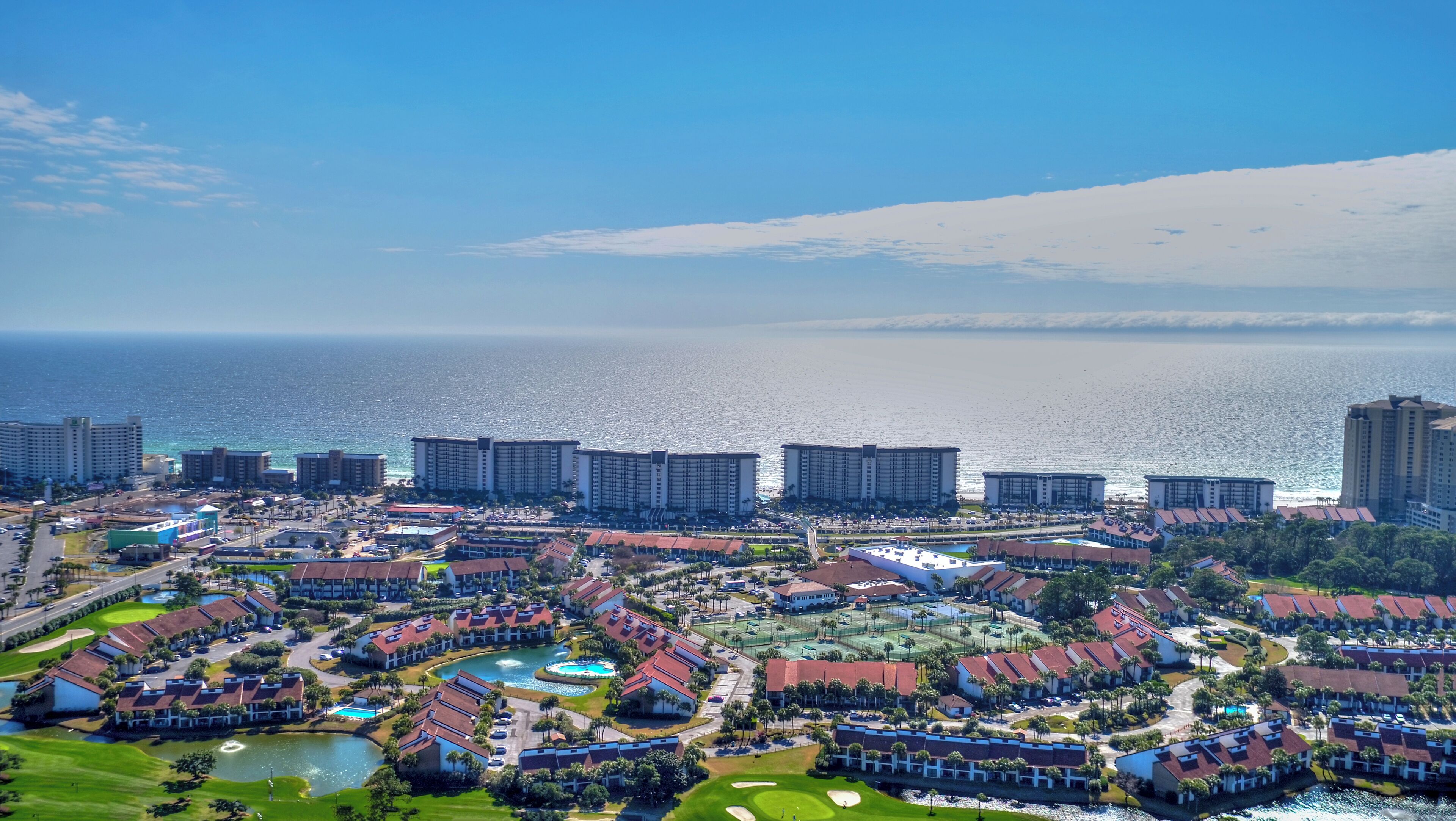 Un resort con varias edificaciones, una piscina y vistas al océano.