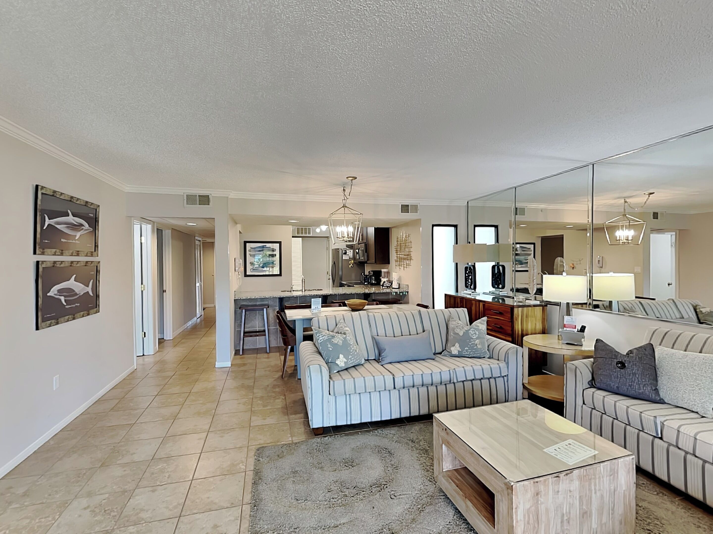A spacious living room with a sofa, coffee table, and a dining area with a kitchen in the background.
