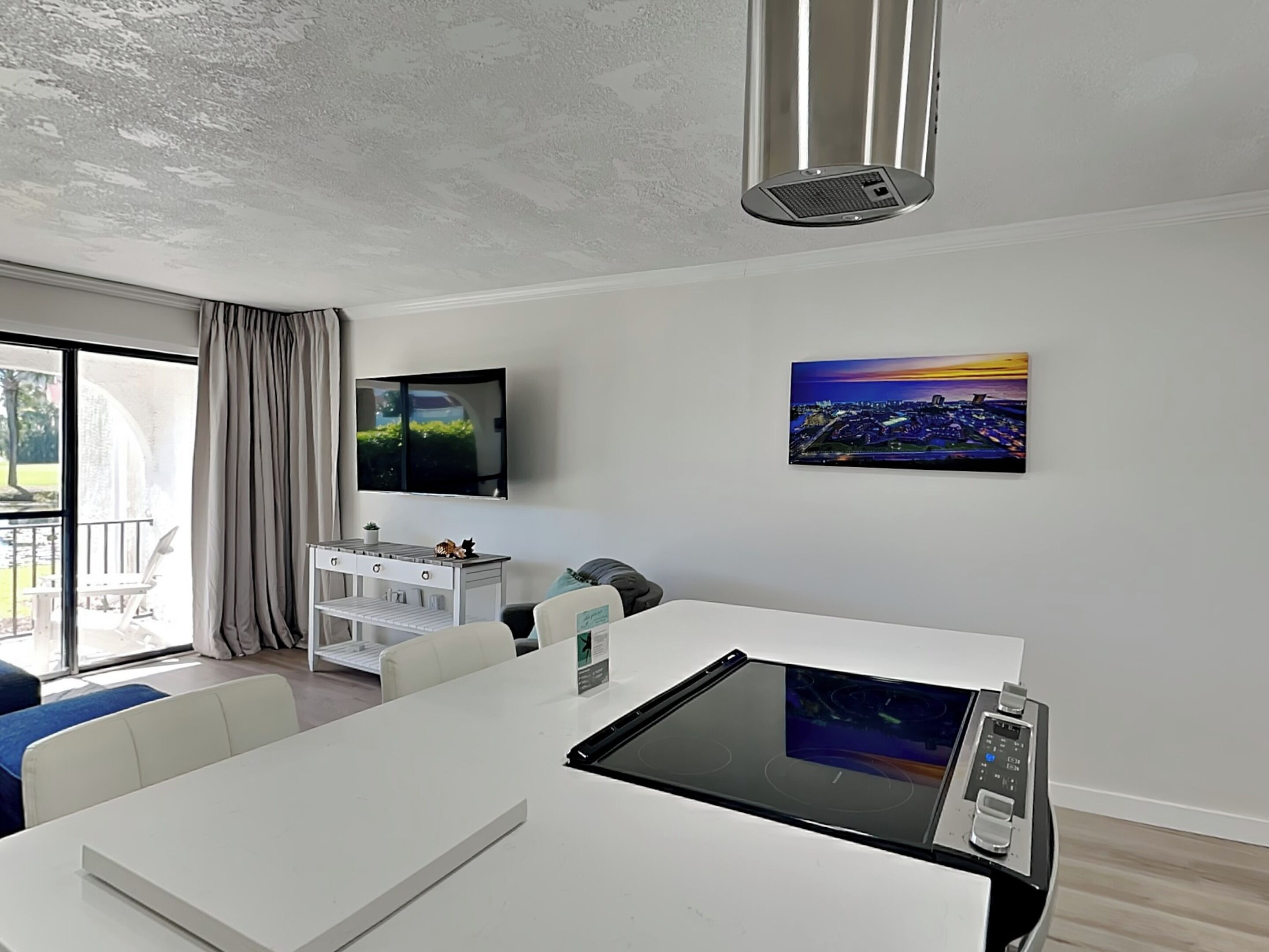 Una sala de estar moderna con una mesa de comedor blanca, un televisor de pantalla plana en la pared y un cuadro con una vista urbana.