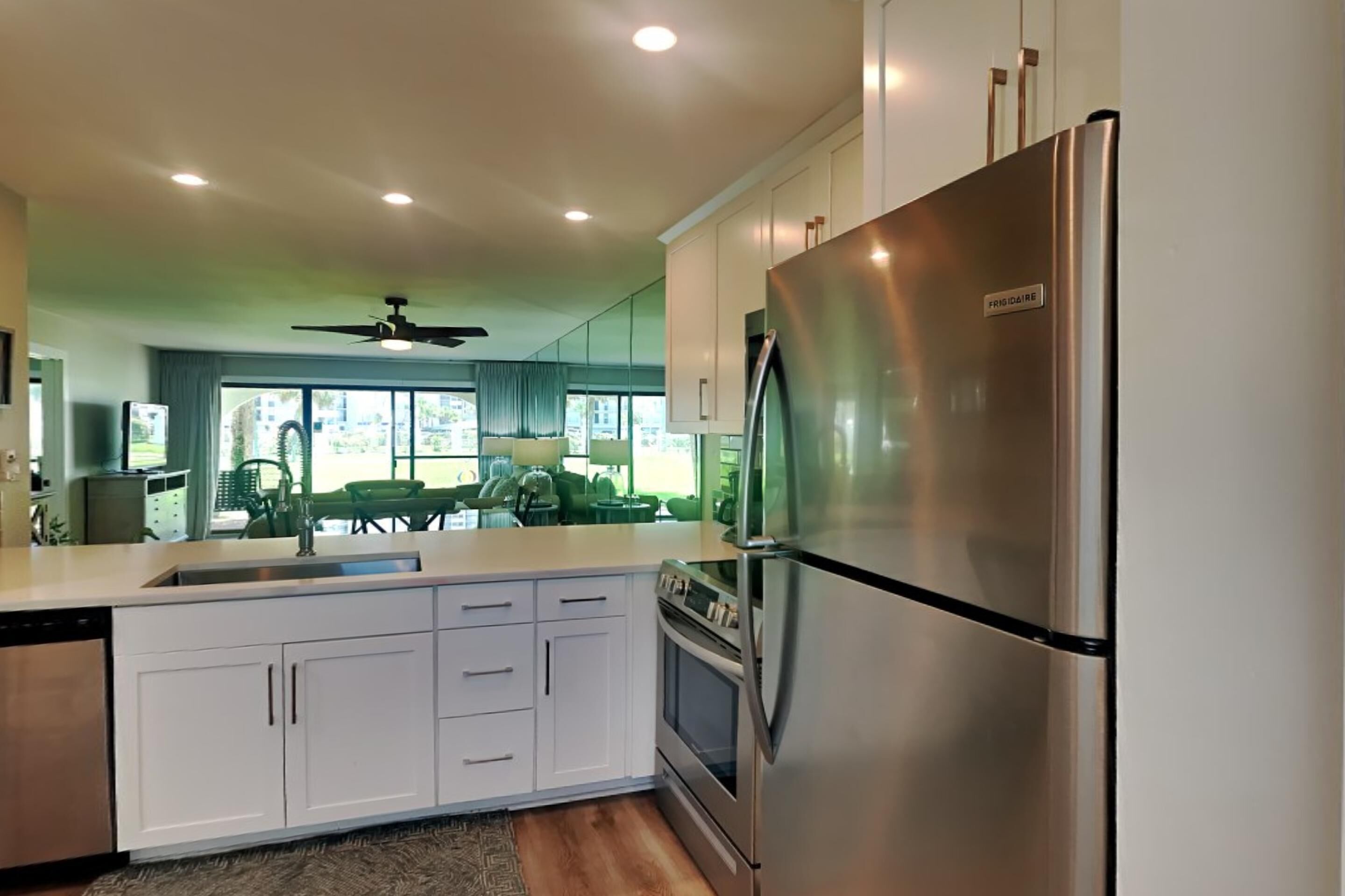 A modern kitchen with white cabinets, a stainless steel refrigerator, and a built-in oven.