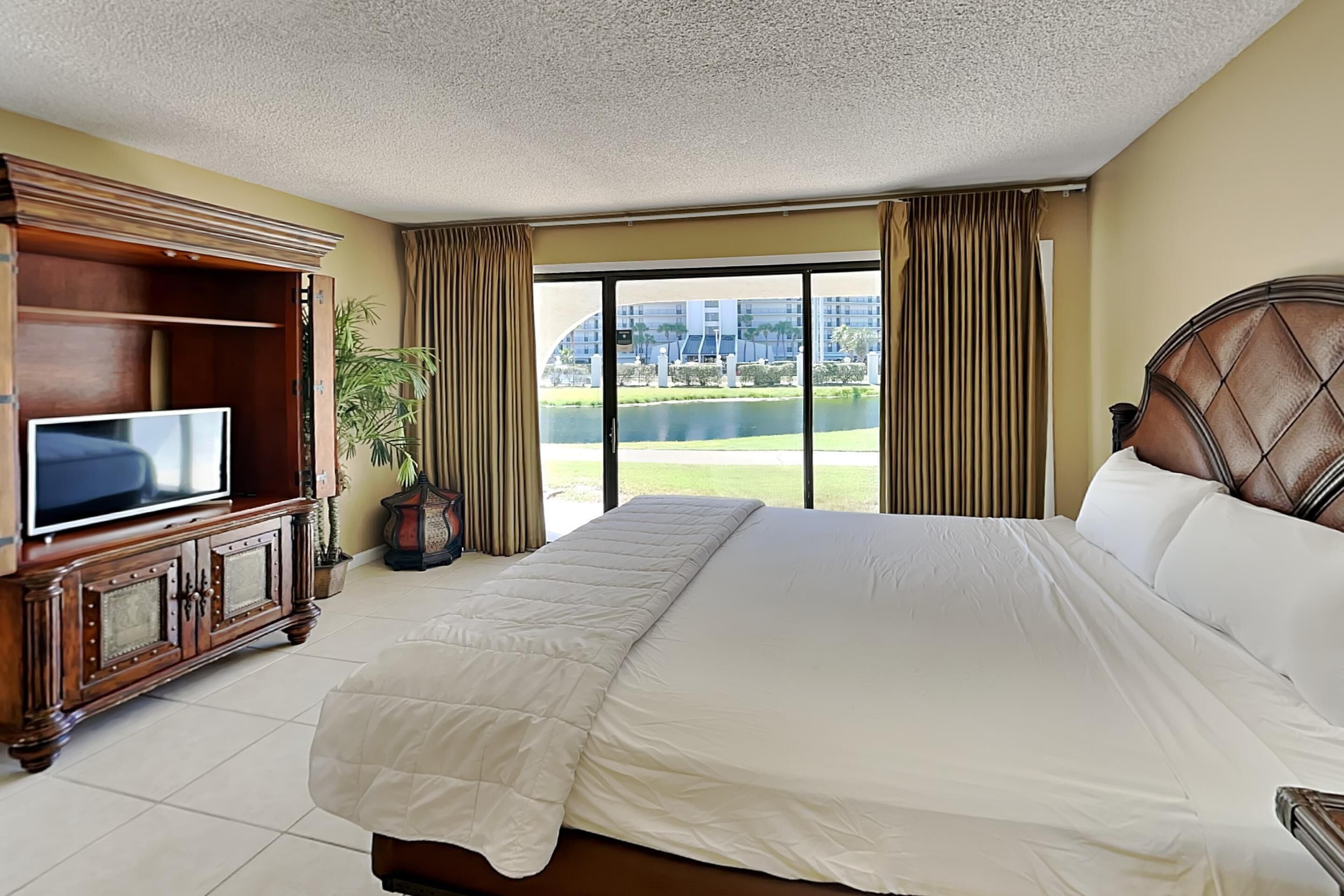 Une chambre d’hôtel avec un grand lit, une télévision, une armoire en bois et une vue sur le paysage urbain par la fenêtre.