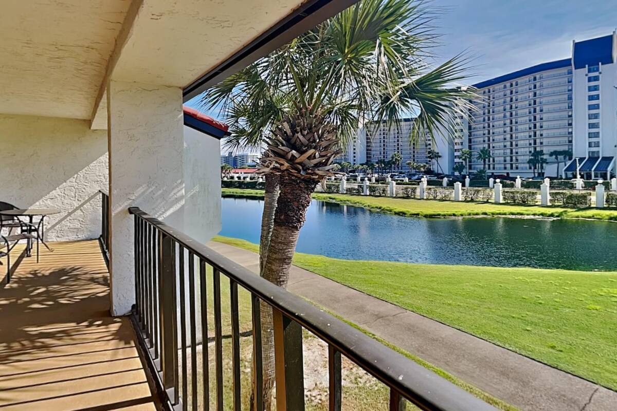 Een balkon met uitzicht op een meer, palmbomen en hoge gebouwen op de achtergrond.