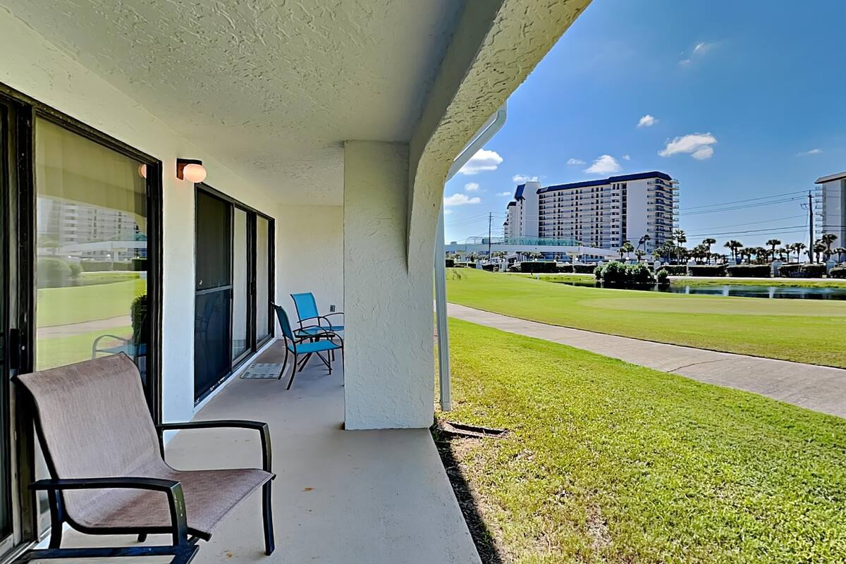 Een hotelbalkon met uitzicht op een golfbaan en een hoog gebouw.