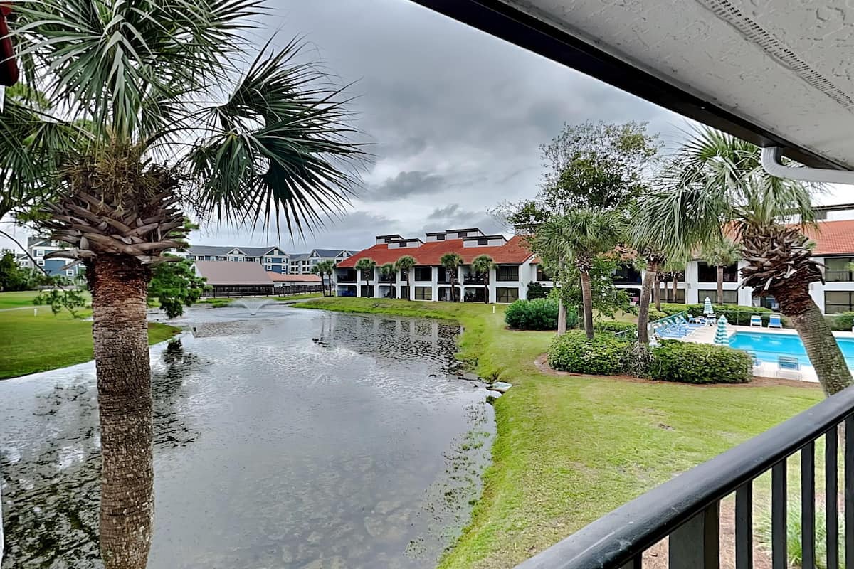 Een uitzicht op een hotel binnenplaats met een waterpartij, palmbomen en een zwembad.