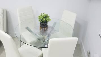 A round glass table with a potted plant in the center, surrounded by white chairs.