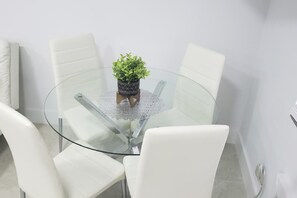 A round glass table with a potted plant in the center, surrounded by white chairs.