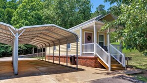 A covered outdoor area with a staircase leading to a house with a porch.