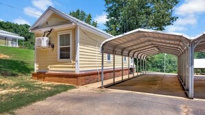 A single-story house with a covered porch, a window, and an air conditioning unit mounted on the wall.