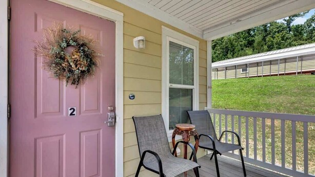 A porch with two chairs, a door with a wreath, and a number '2' sign.