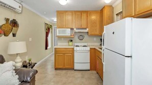 A compact kitchen with wooden cabinets, a white stove, and a refrigerator.