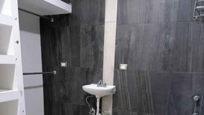 A bathroom with a white sink, dark tiled walls, and a white tiled floor. - departamento bonito en linares NL (Linares)