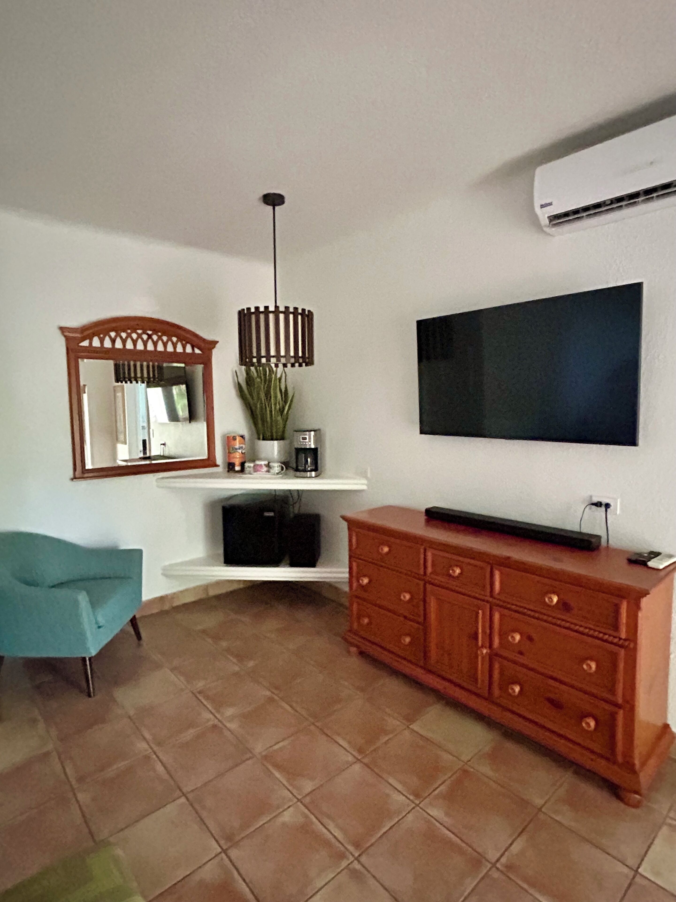 A living room with a TV, wooden cabinet, and a chair.