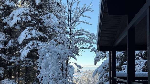 A snowy landscape with a wooden cabin and a view of a snow-covered valley. - The Secret Cabin with hot tube in nature reserve close to Reykjavik  (Hafnarfjordur)