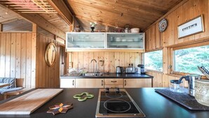 A rustic kitchen with wooden walls, a black countertop, and a built-in stove. - The Secret Cabin with hot tube in nature reserve close to Reykjavik  (Hafnarfjordur)