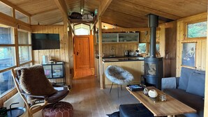 A cozy cabin interior with a wooden interior, a fireplace, a dining area, and a kitchen. - The Secret Cabin with hot tube in nature reserve close to Reykjavik  (Hafnarfjordur)