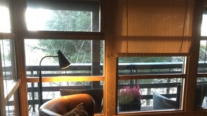 A cozy room with a leather armchair, a small round table, and a window with a view of greenery outside. - The Secret Cabin with hot tube in nature reserve close to Reykjavik  (Hafnarfjordur)