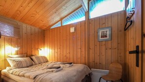 A wooden-paneled room with a bed, a chair, and a radiator. - The Secret Cabin with hot tube in nature reserve close to Reykjavik  (Hafnarfjordur)