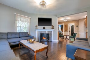 A living room with a fireplace, a sofa, a coffee table, and a television mounted above the fireplace.