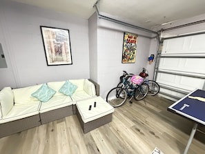 Una habitación con sofá, mesa, bicicleta y puerta de garaje.