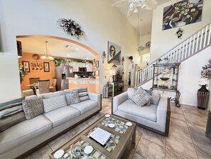 A spacious living area with two sofas, a coffee table, and a kitchen in the background.